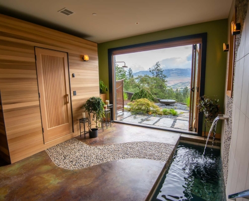 wood, tile and stone accented spa-like retreat master bathroom with sauna, cold plunge bath, folding patio doors and outdoor patio with mountain view