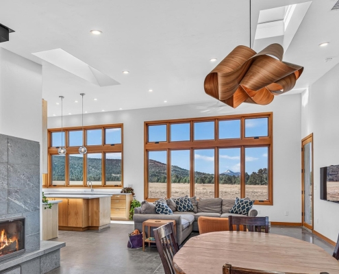 modern open living dining area with fireplace to kitchen with floor to ceiling windows and view of Mt. Shasta