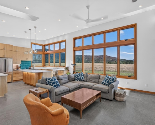vaulted and open concept living to kitchen area with floor to ceiling windows